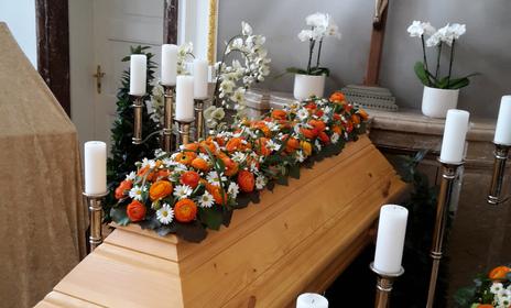 Sargschmuck in Orange und Weiß mit Ranunkeln und Margeriten von Blumen Steinbuch